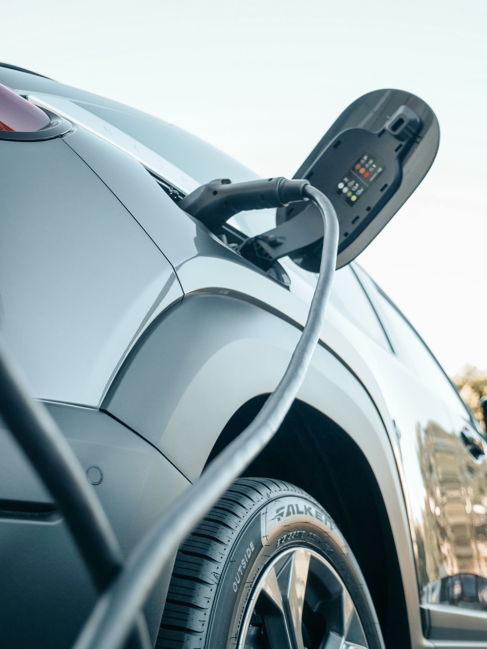 Detalle de un vehículo eléctrico conectado a un punto de recarga.